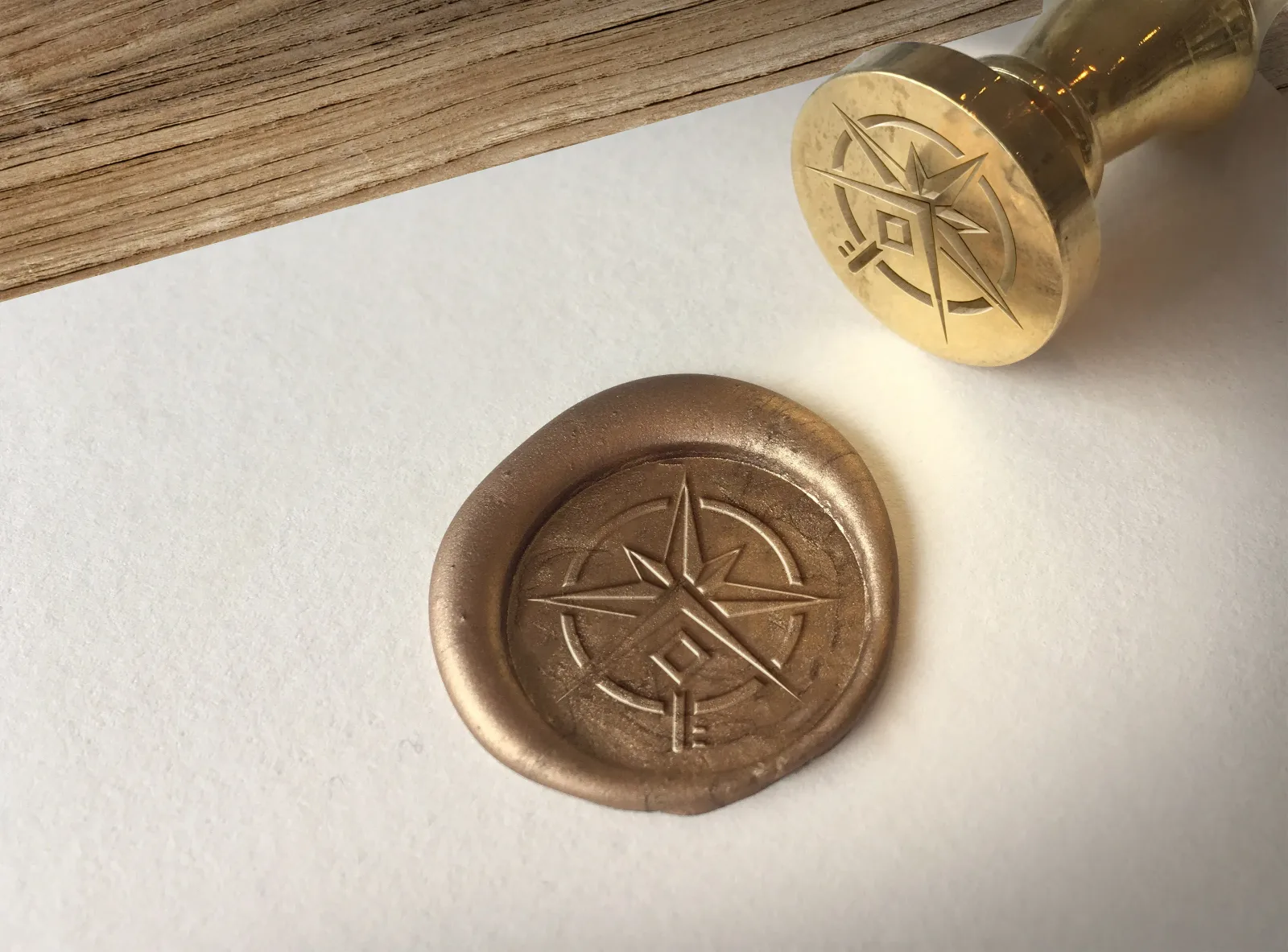Mosiężny stempel z sygnetem Szymański Nieruchomości i odcisk znaku w złotym laku na papierze